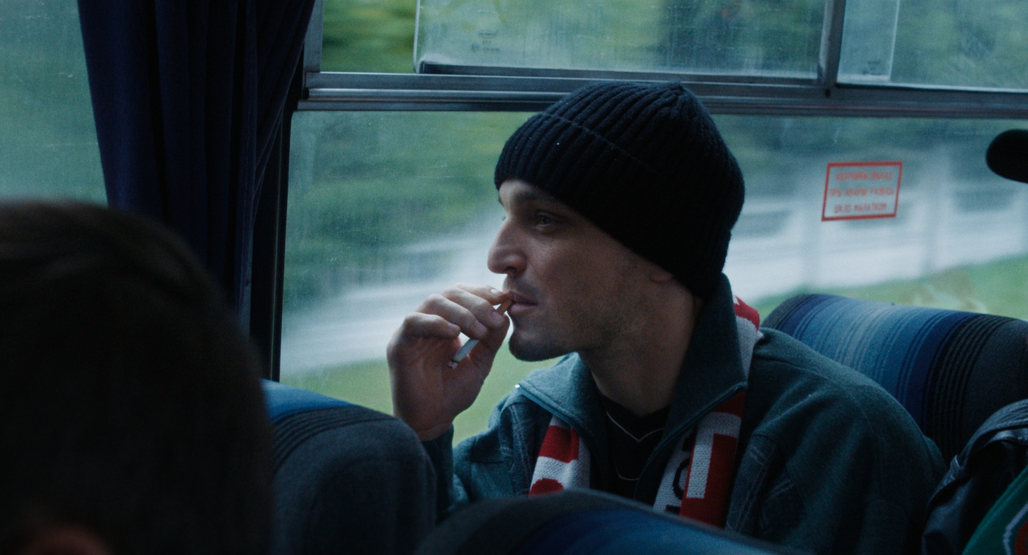 un ragazzo seduto su un pulman con una sigaretta in bocca