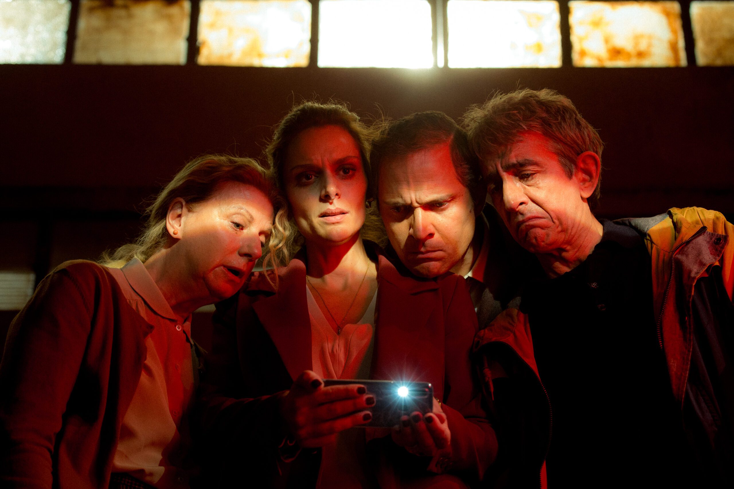 4 persone che guardano lo schermo di un cellulare