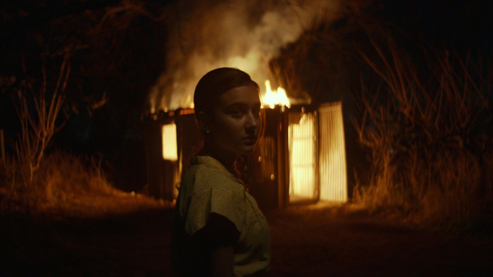 una bambina davanti a un edificio in fiamme