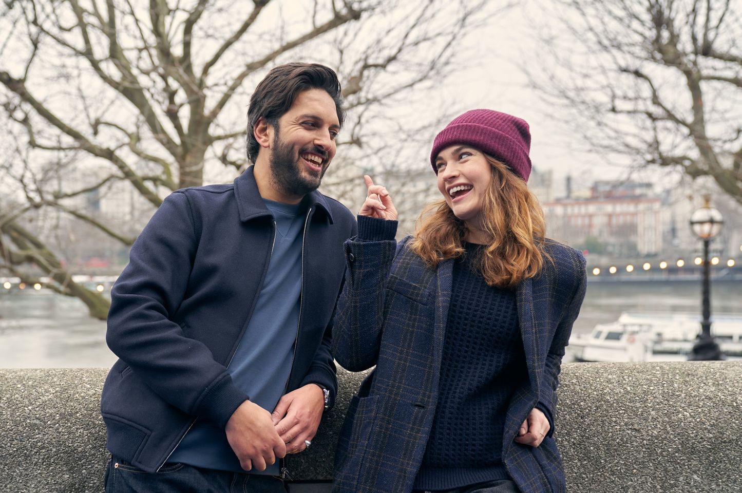 un uomo e una donna che ridono appoggiati a un muretto
