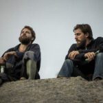 due uomini seduti su una roccia le otto montagne