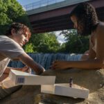 un ragazzo e una ragazza che parlano sulla sponda di un fiume