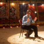 un uomo seduto al centro di una pista di un circo