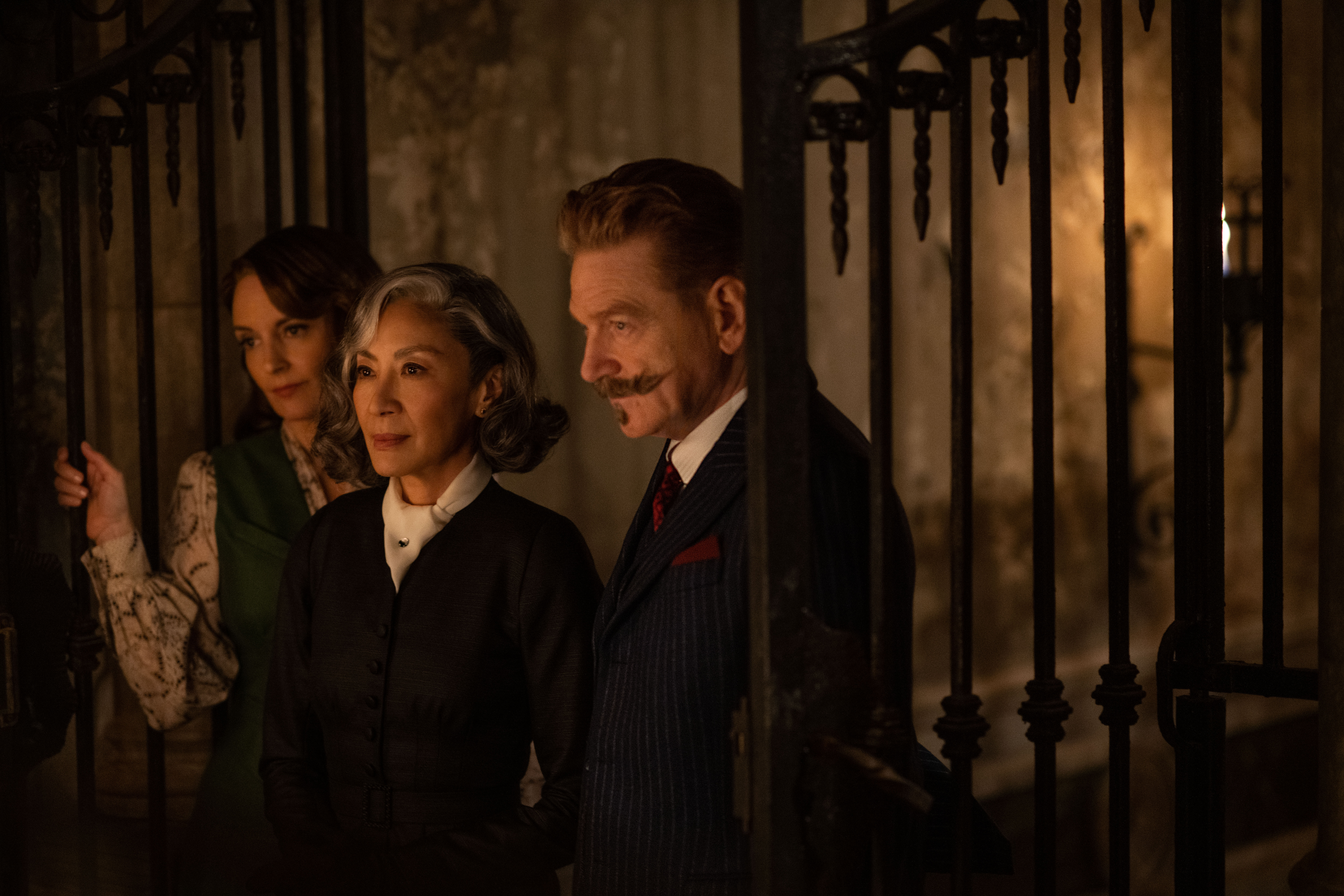 (L-R): Tina Fey as Ariadne Oliver, Michelle Yeoh as Mrs. Reynolds, and Kenneth Branagh as Hercule Poirot in 20th Century Studios' A HAUNTING IN VENICE. Photo by Rob Youngson. © 2023 20th Century Studios. All Rights Reserved.